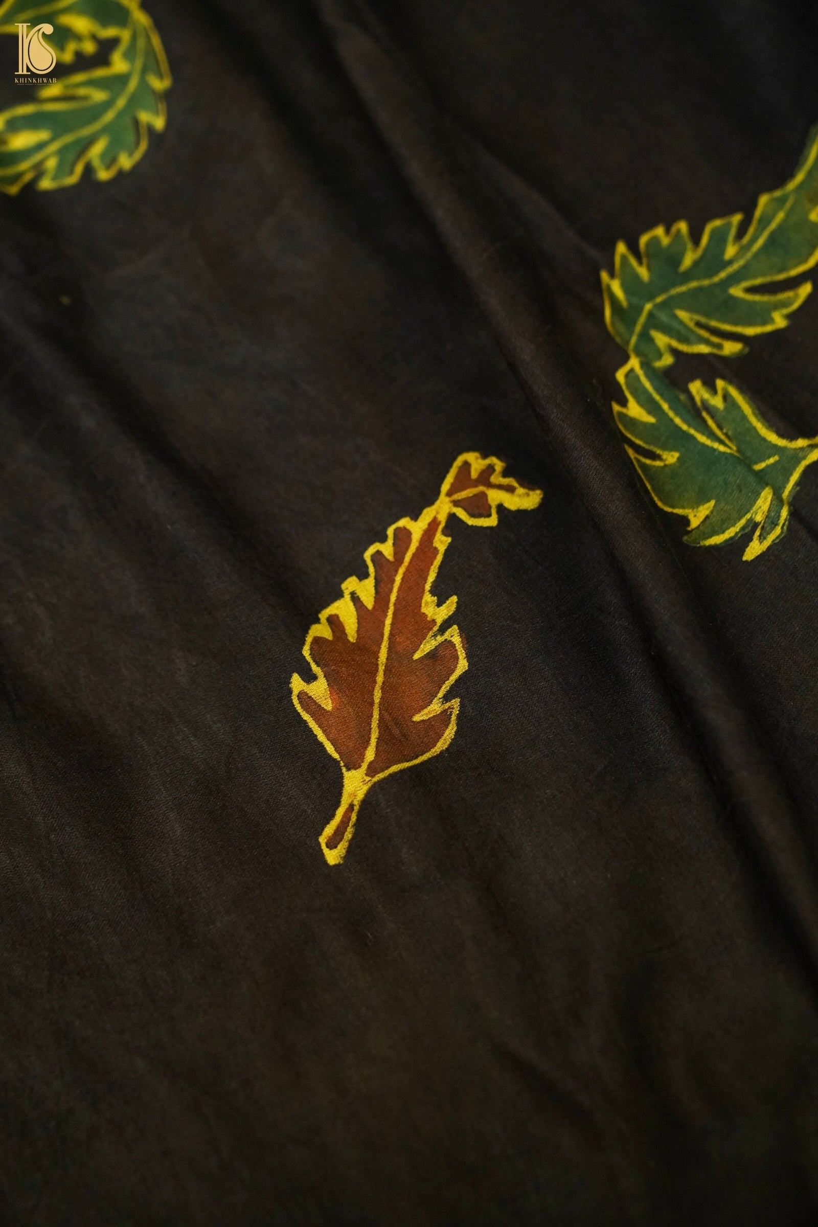 Black fabric with green and gold leaf patterns