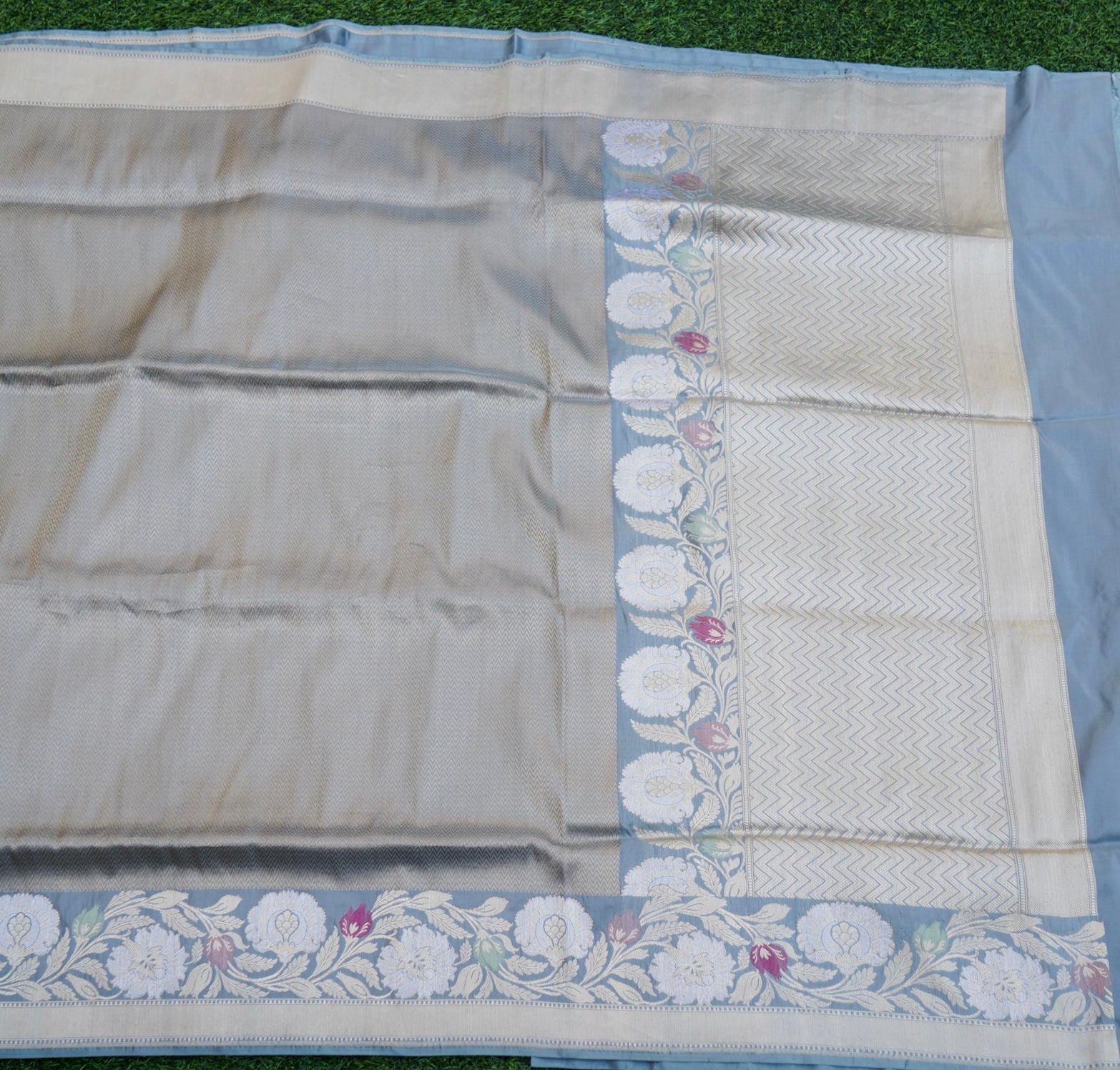 White saree with floral patterns on a blue background