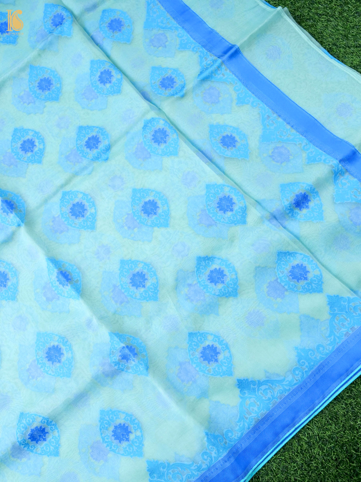 Handwoven Banarasi Organza Silk Saree in ice blue with intricate gold zari work, displayed on a hanger showcasing its elegant drape.