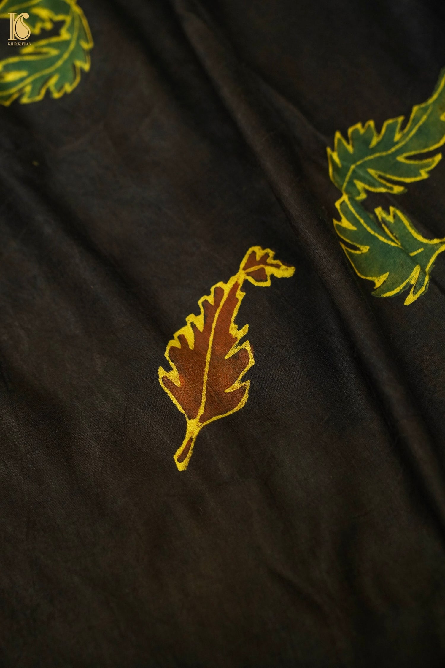 Black fabric with green and gold leaf patterns