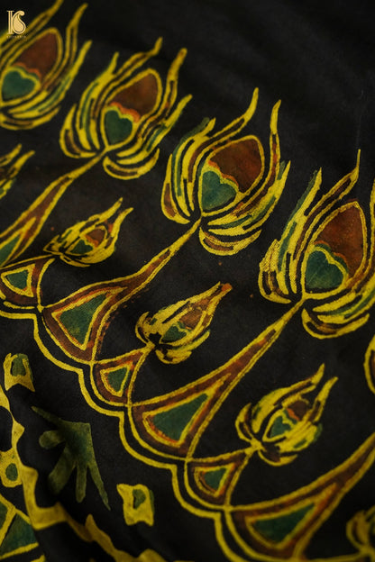 Close-up of a fabric with intricate yellow and green floral pattern on a black background