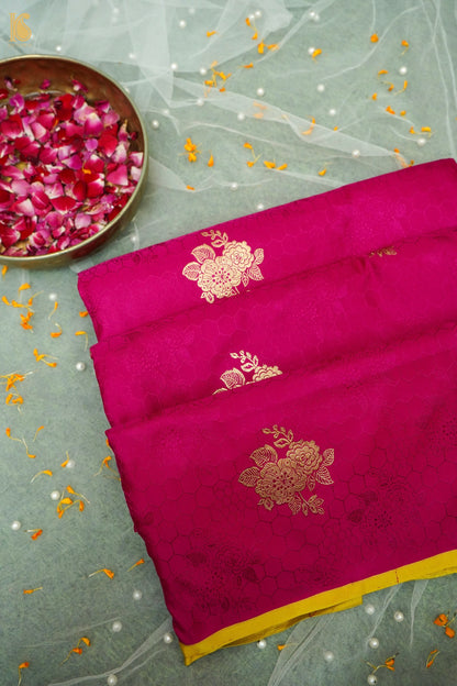 Pink saree with gold embroidery on a light gray background with rose petals.