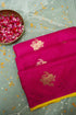 Pink saree with gold embroidery on a light gray background with rose petals.