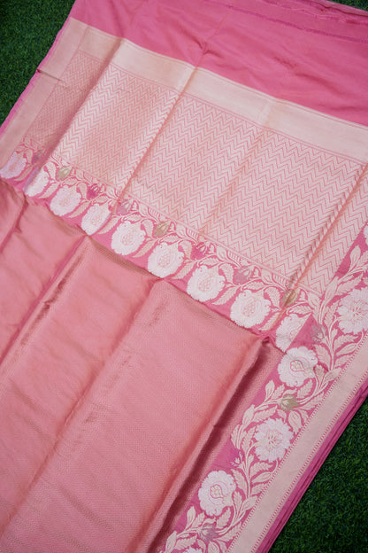 Close-up of a pink saree with white floral patterns on a green background